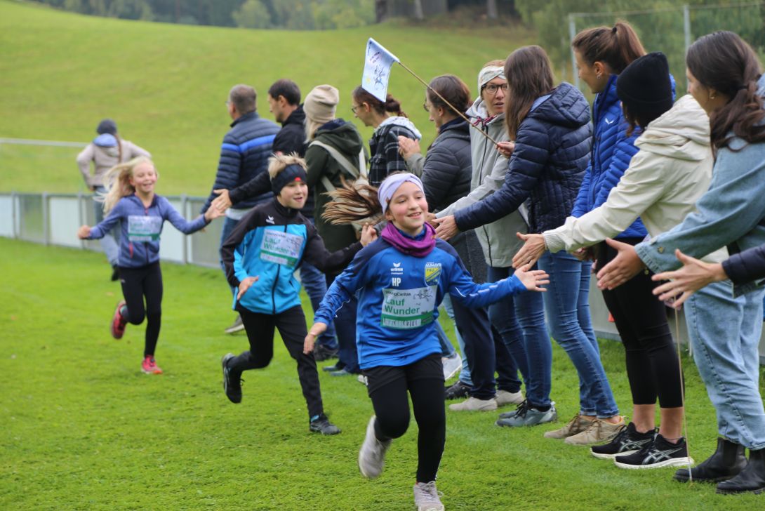 Kinder laufen und klatschen mit Eltern und Lehrer*innen ab