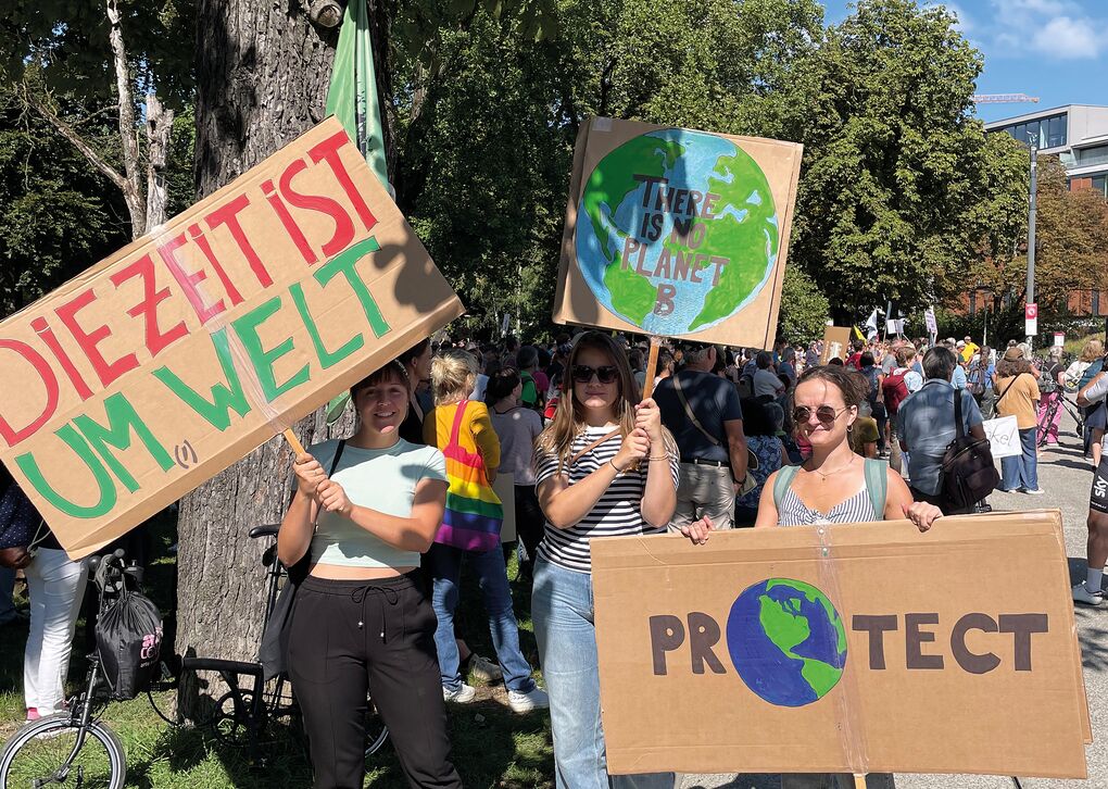 Drei Frauen halten Schilder für den Umweltschutz bei einer Demonstration. Auf den Schildern stehen wichtige Botschaften über unseren Planeten.