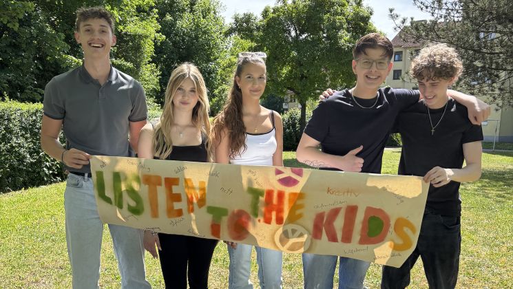 Fünf Jugendliche mit einem Plakat mit der Beschriftung "Listen to the Kids"
