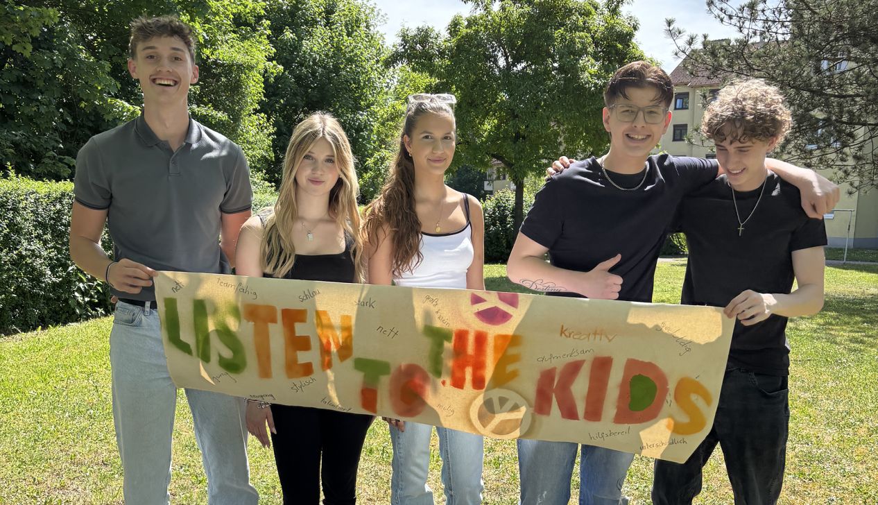 Fünf Jugendliche mit einem Plakat mit der Beschriftung "Listen to the Kids"