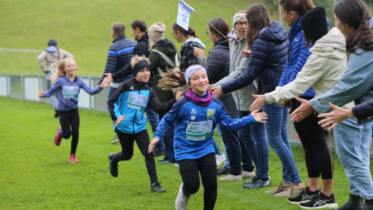 Kinder laufen und klatschen mit Eltern und Lehrer*innen ab