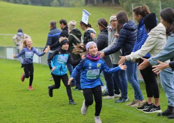 Kinder laufen und klatschen mit Eltern und Lehrer*innen ab
