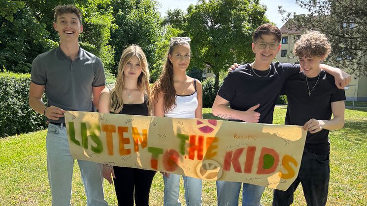 Fünf Jugendliche mit einem Plakat mit der Beschriftung "Listen to the Kids"