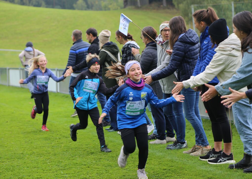 Kinder laufen und klatschen mit Eltern und Lehrer*innen ab